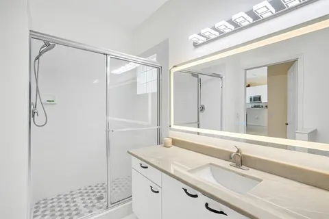 a bathroom with a granite countertop sink a shower and a mirror