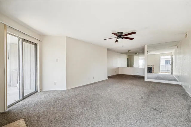 an empty room with ceiling fan and window
