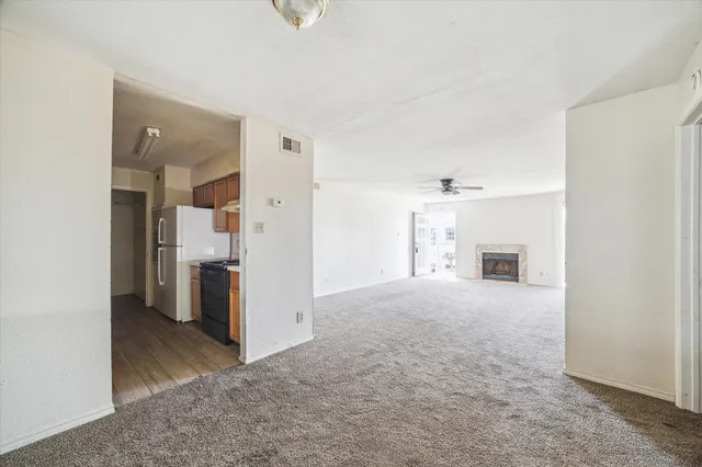 a view of a hallway with white cabinets and a refrigerator