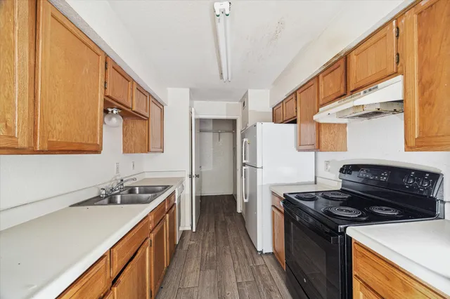 a kitchen with a sink stove top oven and refrigerator