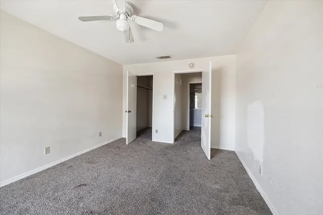 an empty room with a ceiling fan and carpet