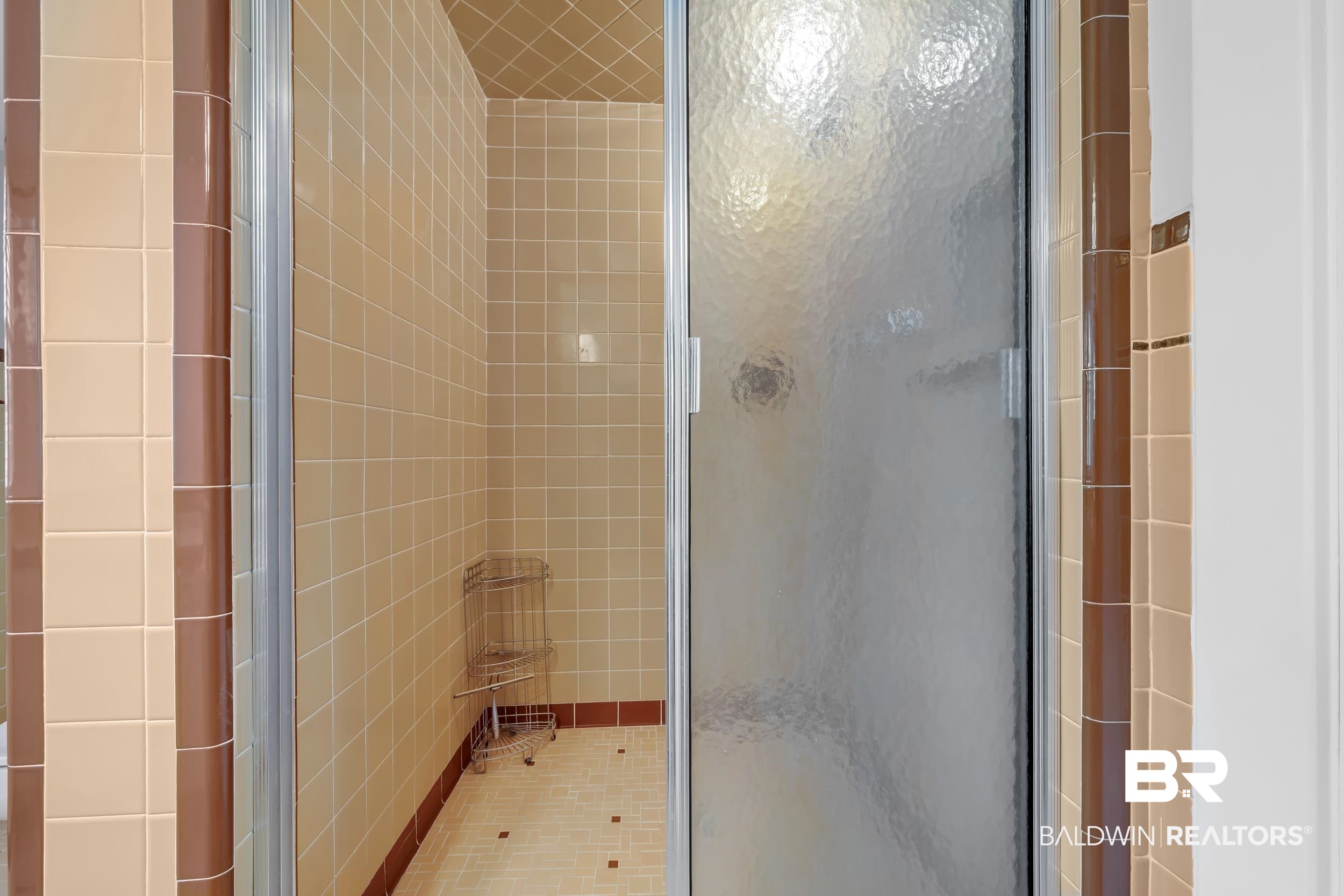 43199 Pine Grove Road Bay Minette, AL 36507 - Photo 59 of 71 Walk-in shower featuring a sliding frosted glass door, light beige square wall tiles, and brown accent tiles