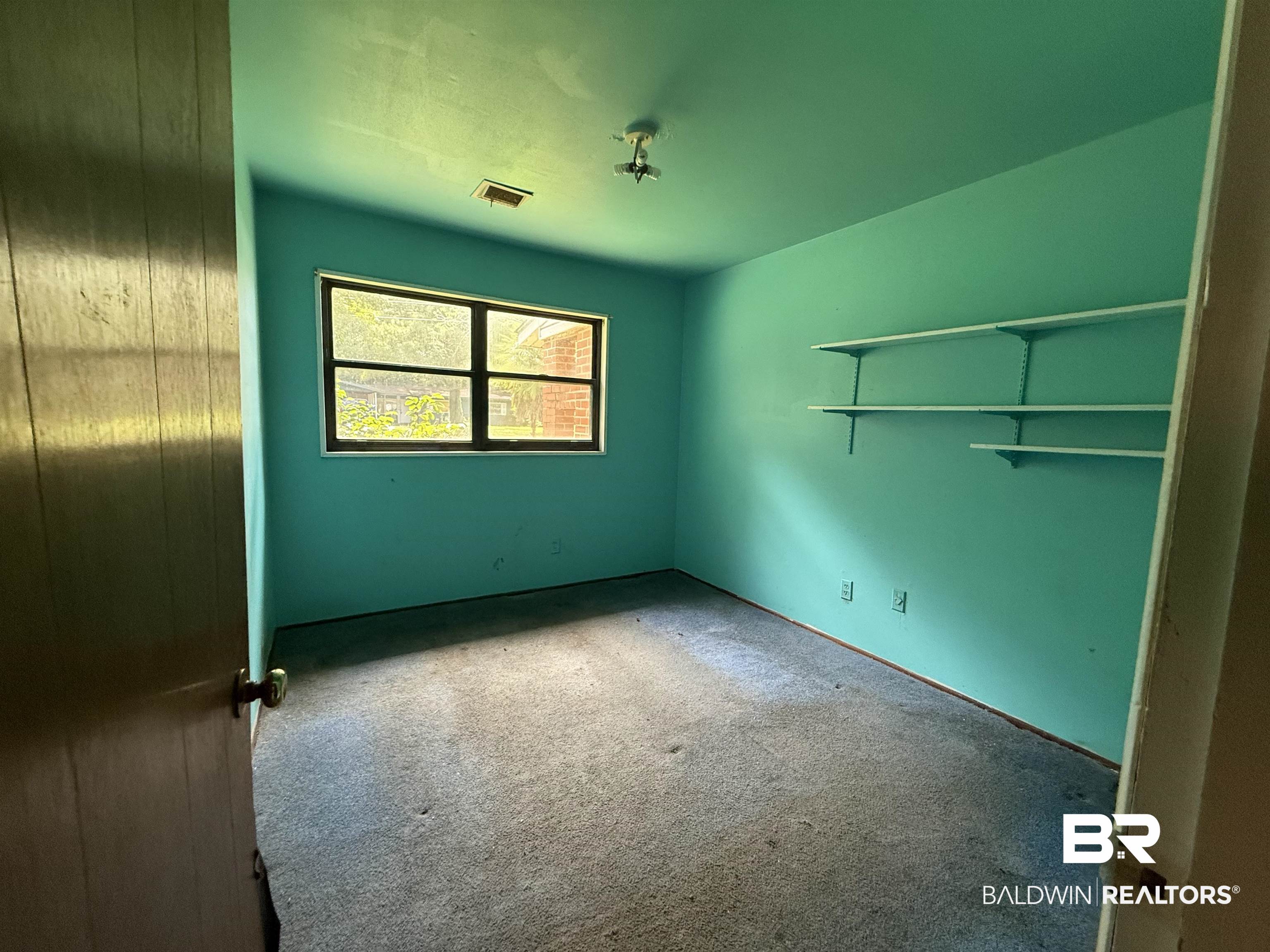 711 Wilshire Road Mobile, AL 36609 - Photo 7 of 11 Room with adjustable wall-mounted shelving, a window with exterior views, and ceiling-mounted light fixture