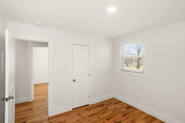an empty room with wooden floor and window