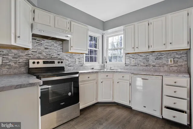 a kitchen with granite countertop white cabinets stainless steel appliances and a sink