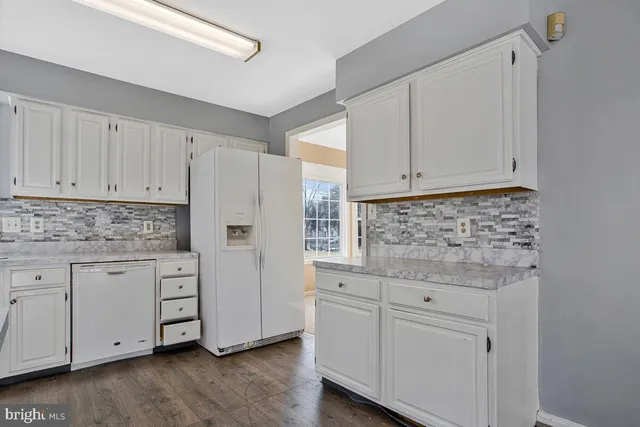 a kitchen with granite countertop white cabinets and white appliances