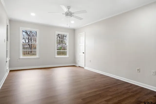 a view of an empty room with wooden floor and a window