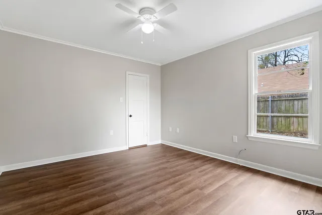 a view of an empty room with wooden floor and a window