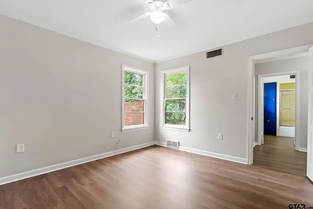 an empty room with wooden floor and windows