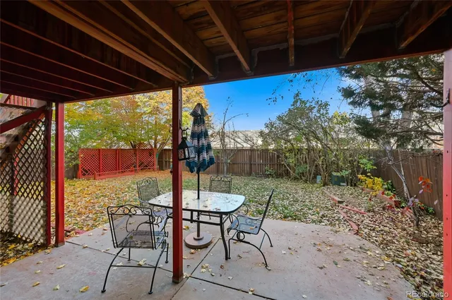 a view of a patio with table and chairs and wooden floor next to a yard