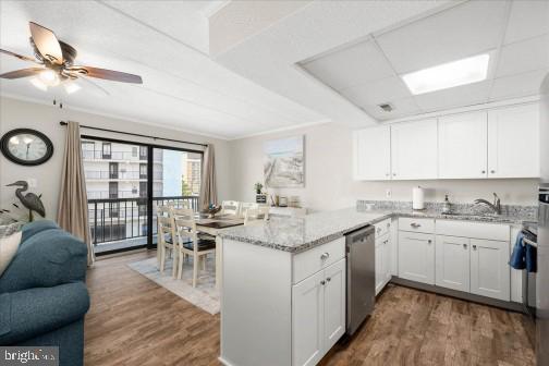 11 134th Street, Unit 205 Ocean City, MD 21842 - Photo 8 of 29 a open kitchen with stainless steel appliances granite countertop a stove top oven a sink a dining table and chairs with wooden floor