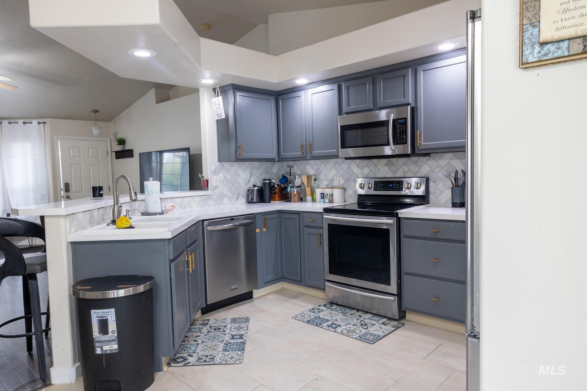 14409 Raleigh Court Caldwell, ID 83607 - Photo 6 of 15 Kitchen featuring gray cabinetry, stainless steel appliances, herringbone tile backsplash, recessed lighting, and light-toned flooring