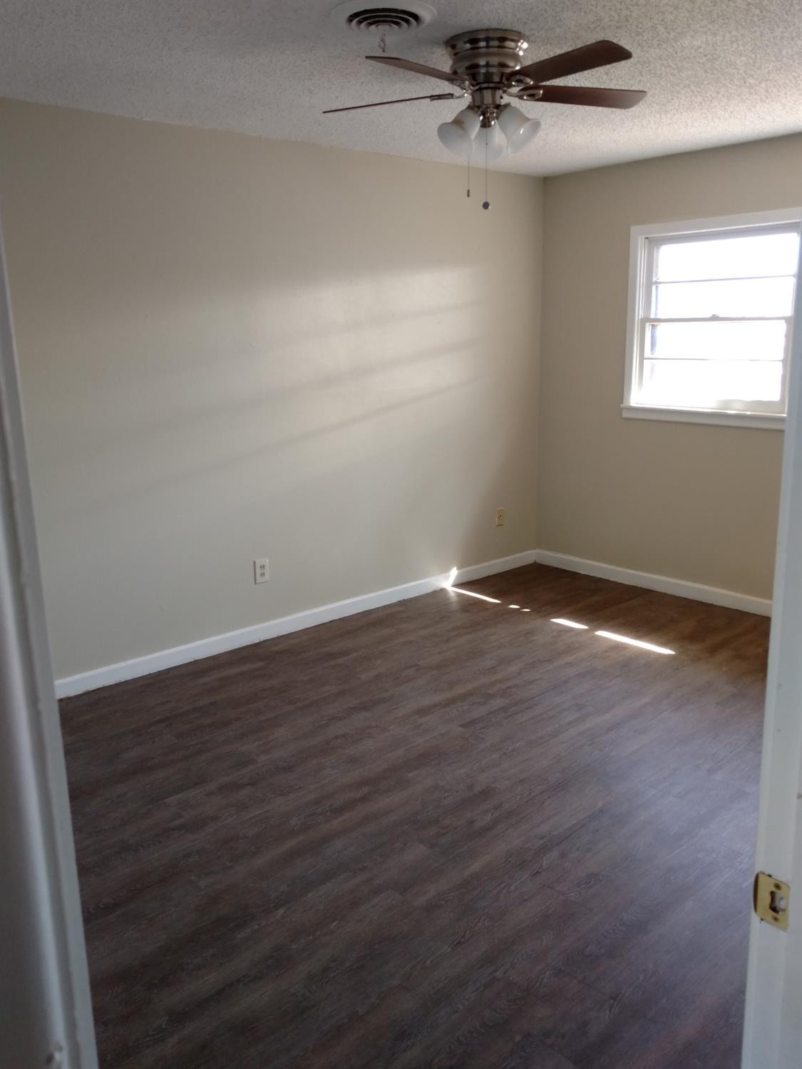 2812 43rd Street, Unit 6 Lubbock, TX 79413 - Photo 8 of 10 an empty room with wooden floor fan and windows