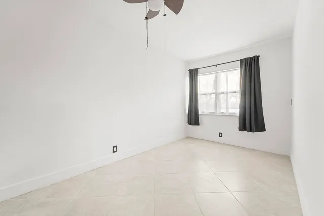 an empty room with a ceiling fan and a window