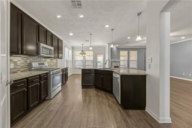 a large kitchen with stainless steel appliances and wooden cabinets