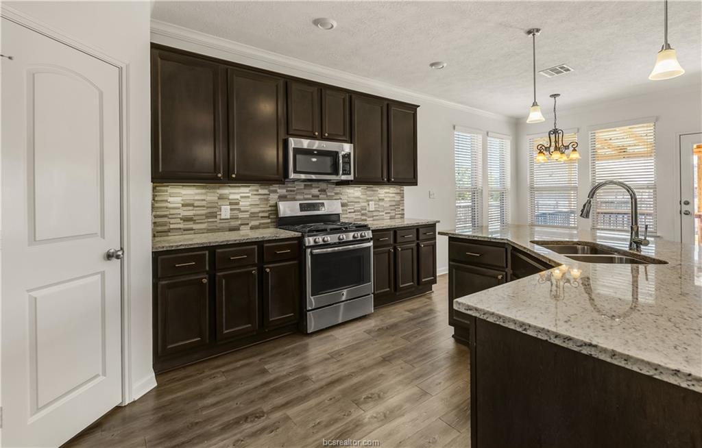 4159 Shallow Creek Loop College Station, TX 77845 - Photo 7 of 32 a kitchen with stainless steel appliances granite countertop a sink a stove top oven a counter space and cabinets