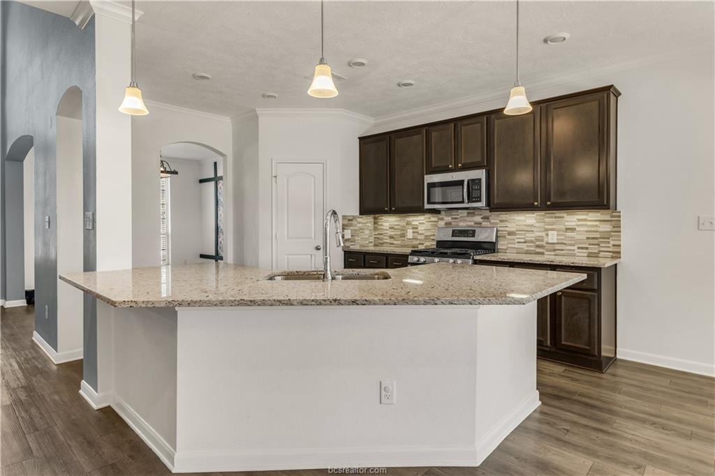 4159 Shallow Creek Loop College Station, TX 77845 - Photo 8 of 32 a kitchen with kitchen island granite countertop a sink stove and refrigerator
