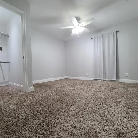 a view of an empty room with a chandelier fan