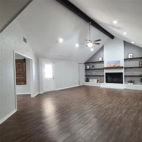 an empty room with wooden floor and a fireplace
