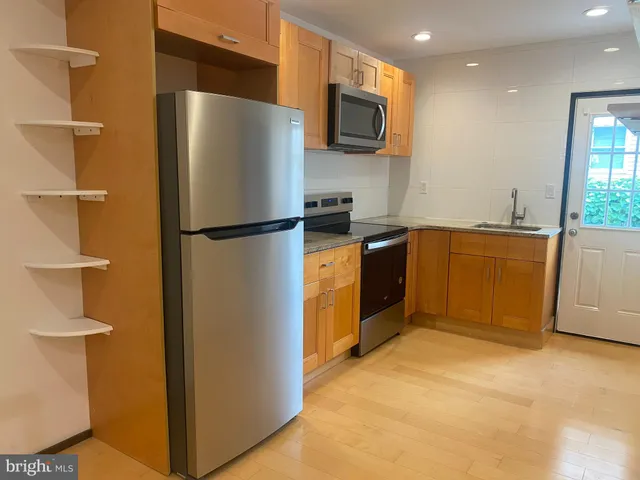 a kitchen with stainless steel appliances granite countertop a sink a stove a microwave and grey cabinets
