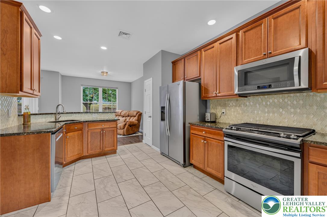 4236 Creek Road Allentown, PA 18104 - Photo 11 of 47 Rich wood cabinetry and stone countertops anchor this modern kitchen with durable tile flooring.