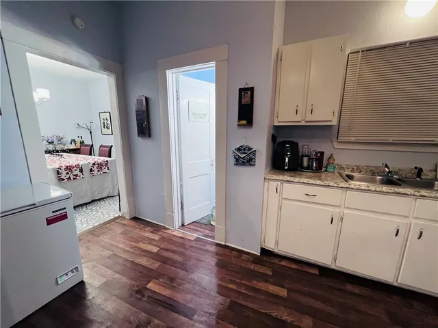 a kitchen with granite countertop white cabinets and wooden floor