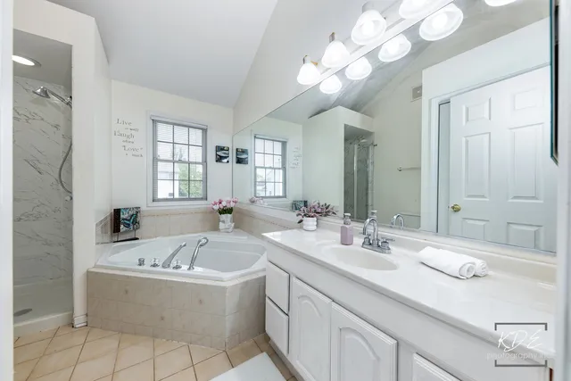 a bathroom with a bathtub a double vanity sink and mirror