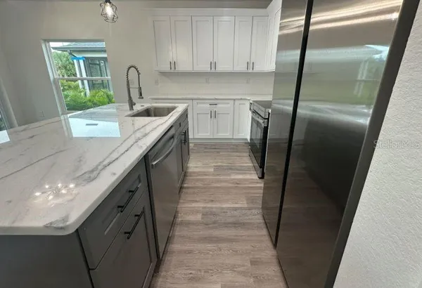 a kitchen with kitchen island a stove a refrigerator and a sink