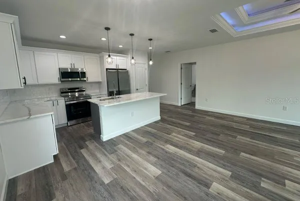 a kitchen with kitchen island a counter top space a refrigerator cabinets and a window