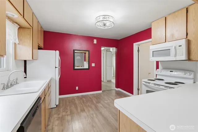 a kitchen with stainless steel appliances a stove a refrigerator white cabinets and wooden floor