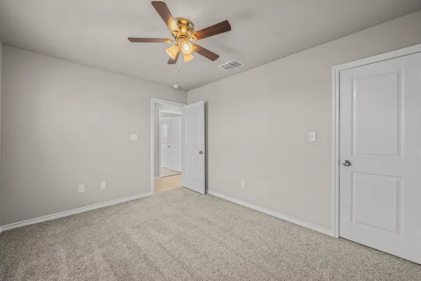 an empty room with a ceiling fan and carpet