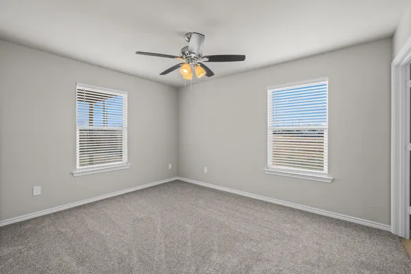 a view of an empty room with a window and chandelier fan