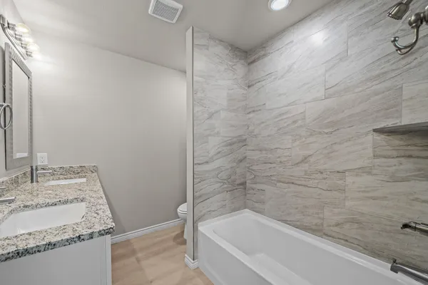 a bathroom with a granite countertop sink and a bathtub