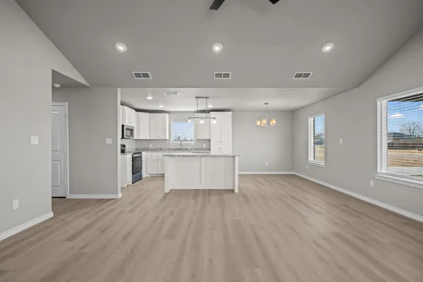 a kitchen with stainless steel appliances granite countertop a stove top oven a sink dishwasher and a refrigerator with wooden cabinets