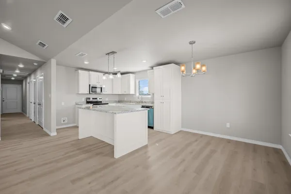 a kitchen with stainless steel appliances granite countertop a sink a stove and microwave with wooden floor