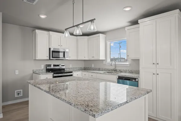 a kitchen with kitchen island a stove top oven a sink cabinets and wooden floor