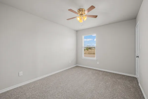 an empty room with a window and a ceiling fan