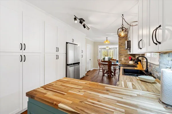 a kitchen with stainless steel appliances a white table chairs and a wooden floor