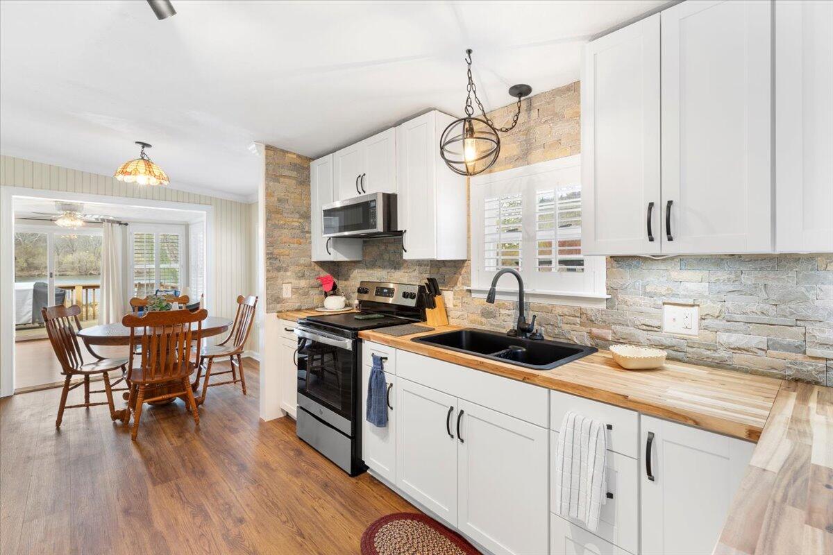 3729 Clark Road Hiwassee, VA 24347 - Photo 16 of 52 a kitchen with stainless steel appliances a white table chairs and a wooden floor