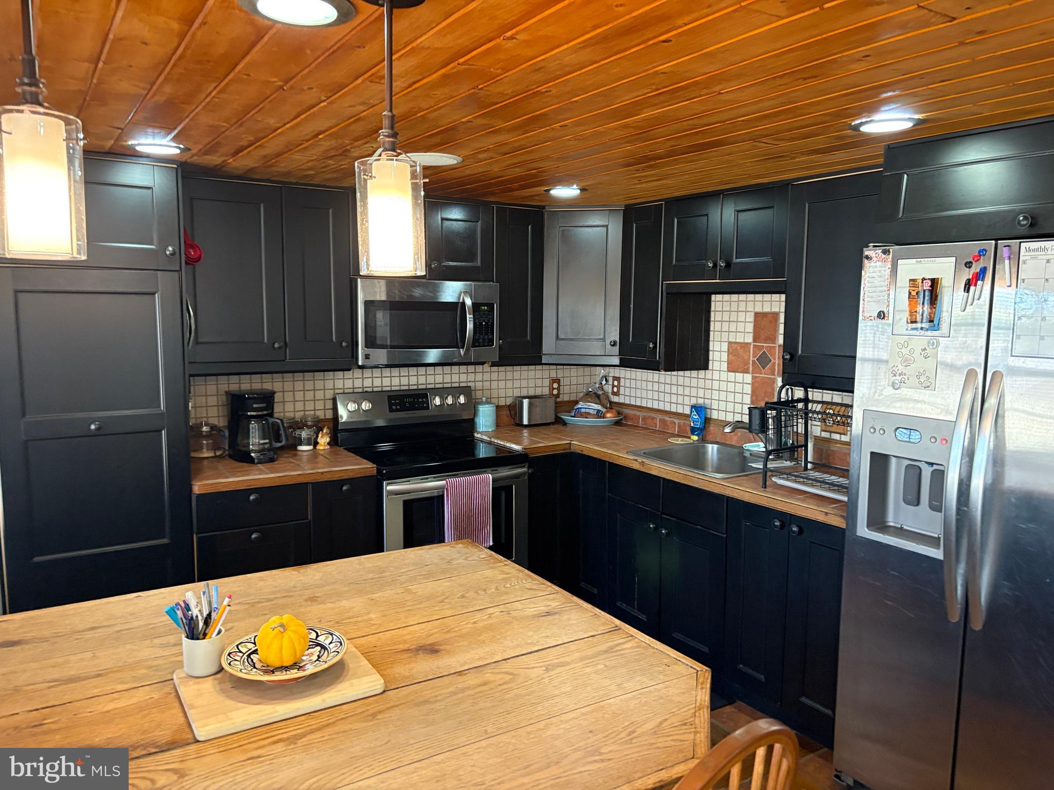 2398 Frenchtown Road Port Deposit, MD 21904 - Photo 10 of 17 a kitchen with stainless steel appliances kitchen island granite countertop a refrigerator a stove top oven a sink dishwasher and wooden cabinets