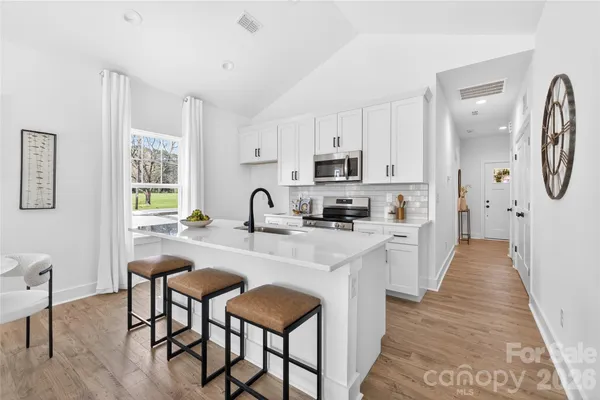 a large kitchen with kitchen island granite countertop a table chairs sink and cabinets