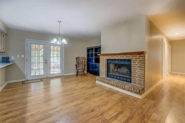 a view of an empty room with wooden floor fireplace and a window