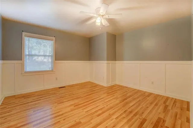 a view of empty room with wooden floor and fan