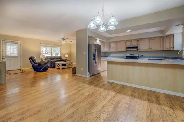 a view of a kitchen with kitchen island granite countertop wooden floor stainless steel appliances and living room view