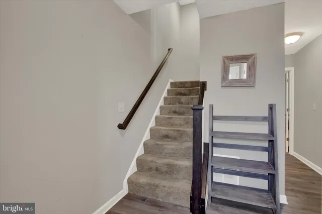 a view of staircase with wooden floor and white walls