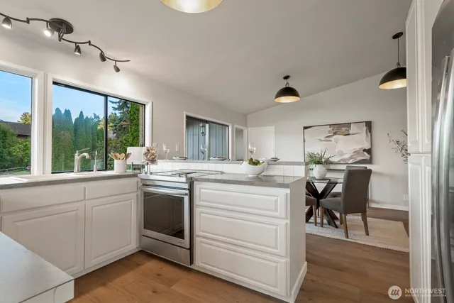 a kitchen with a stove and white cabinets with wooden floor
