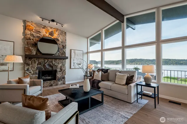 a living room with furniture a fireplace and floor to ceiling windows