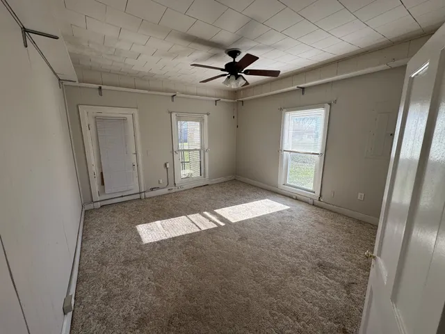 an empty room with windows and fan