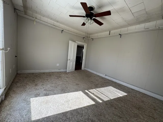 an empty room with a ceiling fan and carpet