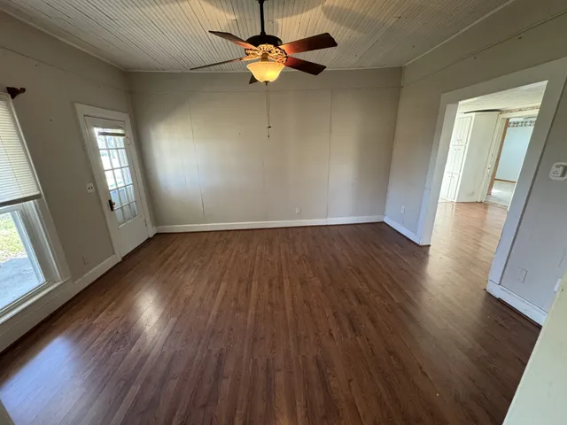 a view of empty room with wooden floor and fan